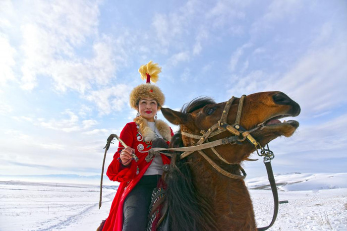 哈萨克族姑娘骑着骏马奔驰在一望无际的雪地上.