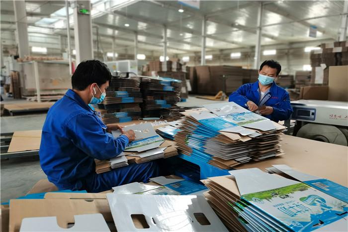阿克苏市依干其乡长兴社区弘宇纸箱厂的工人在生产线上忙碌着生产纸箱