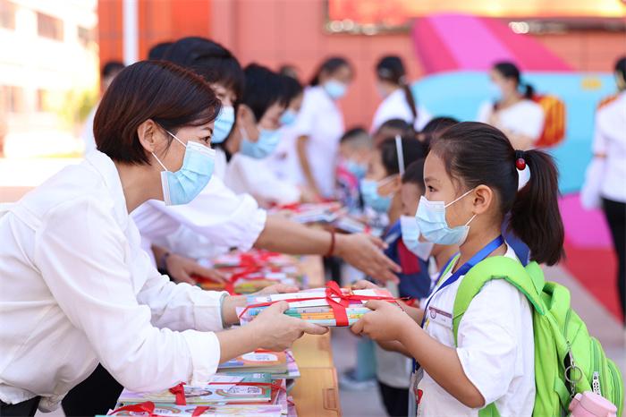 "库车市第十三小学的老师为学生放发新书,并送上和蔼可亲的笑容和叮咛